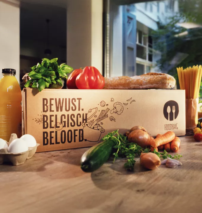 Campaign key visual for Foodbag’s Effie Award case by Springbok Agency, showing fresh food ingredients arranged creatively with Foodbag's slogan on a box saying 'Conscious, Belgian, Our promise' in Dutch.