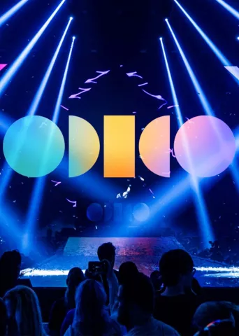 Odido logo on a picture of stage with moving LED beams.